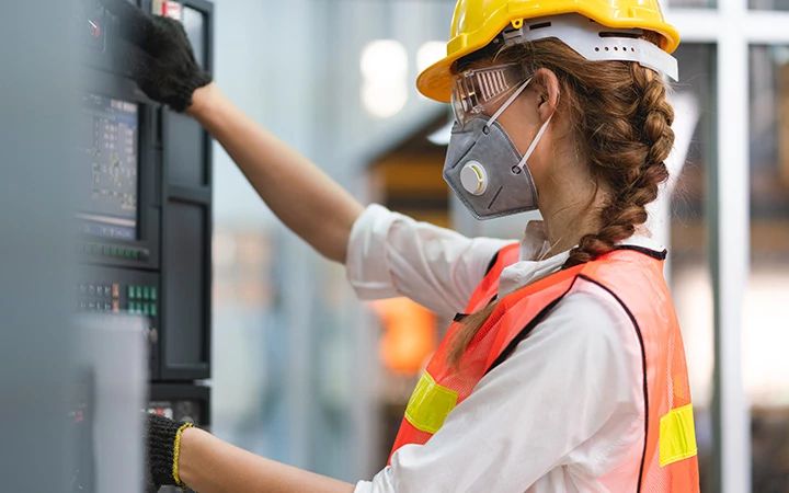 Woman in personal protective equipment installs panel.