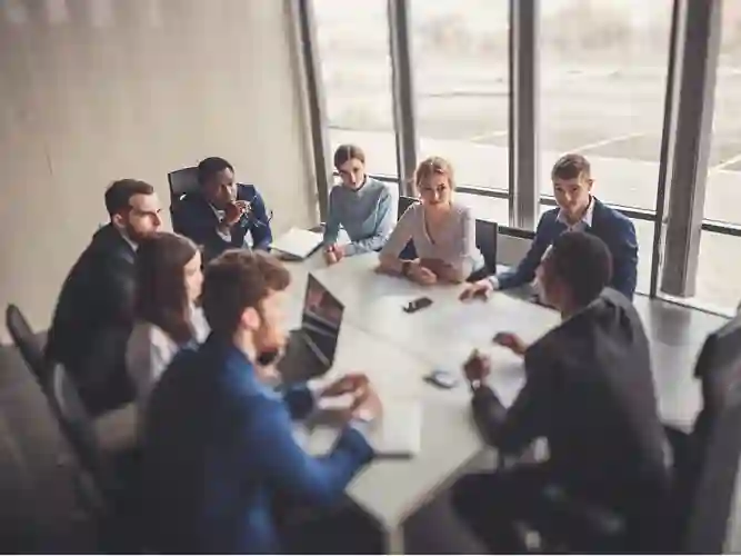 Grupo de hombres y mujeres vestidos como profesionales sentados en torno a una mesa de conferencias